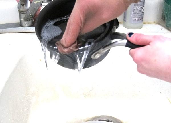 lavar una sartén con un trozo de pantimedias