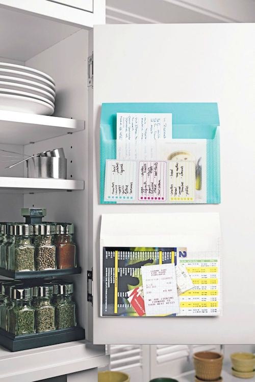 Un armario de cocina blanco con espacio de almacenamiento en la puerta para guardar listas de compras y papeles.