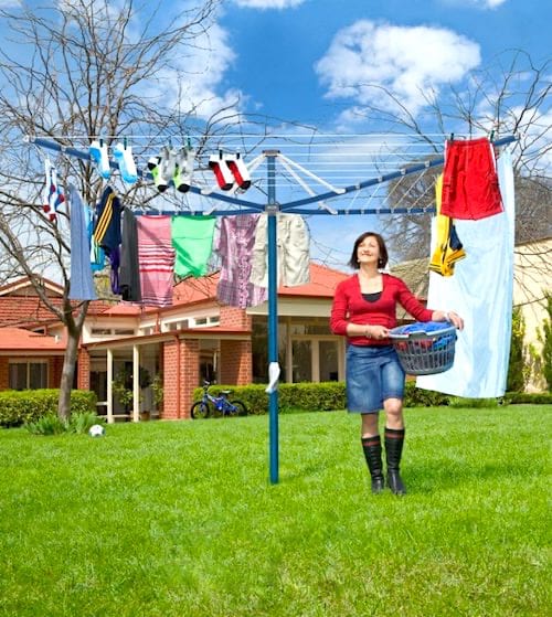 Una mujer secando la ropa al sol en el jardín con un tendedero