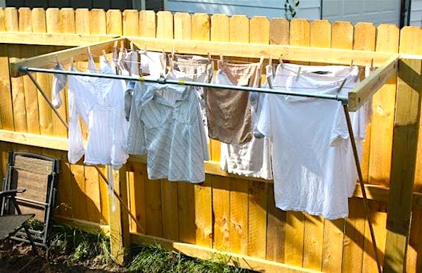 Un tendedero conectado a una valla de madera en un jardín para secar la ropa al sol.