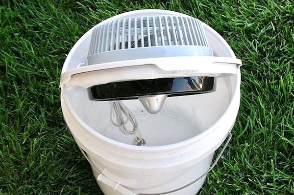Un ventilador insertado en un balde para hacer una casa de aire acondicionado.