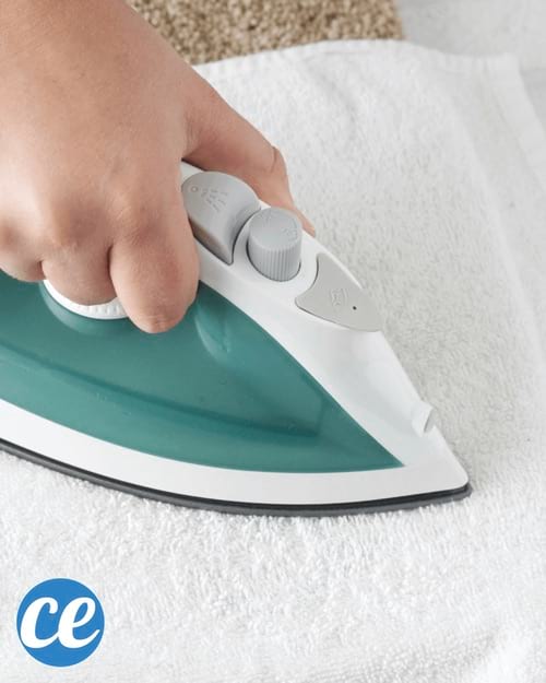 Una mano quitando una mancha de marcador permanente de la alfombra con una plancha.
