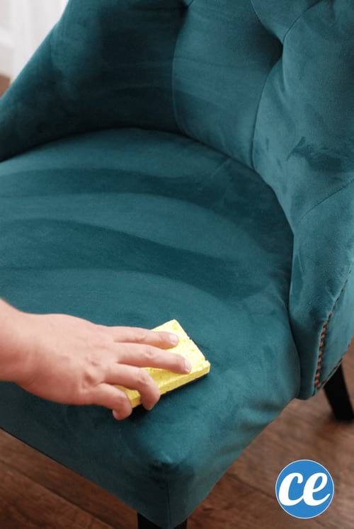 Una mano quitando una mancha indeleble de rotulador de un sillón de microfibra.