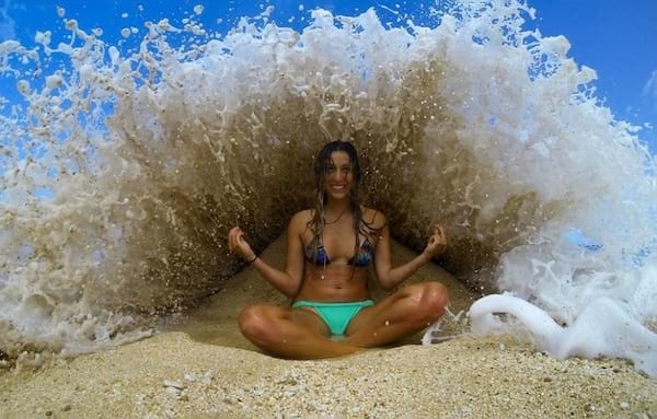 Mujer haciendo yoga en una playa junto al agua