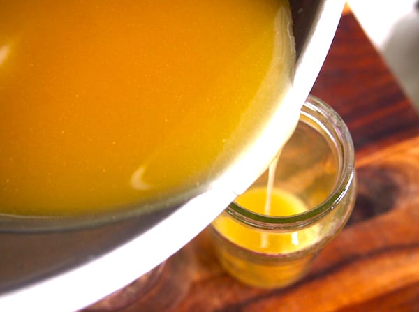 Miel derretida, aceite de almendras dulces y cera de abejas vertidos en un frasco de vidrio para obtener una crema hidratante casera.