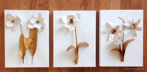 ثلاثة إطارات للصور معلقة على حائط مزين بعدة أزهار مزيفة