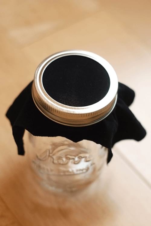 frasco de vidrio cerrado con una pieza de pantimedias de nailon negro