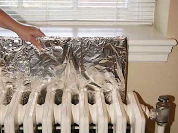 Paper d'alumini col·locat darrere del radiador de ferro colat per augmentar la seva potència
