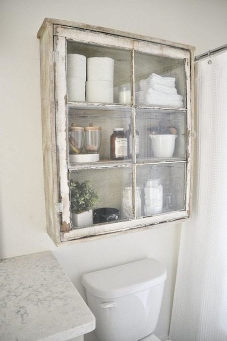 Un armario de vidrio vintage para guardar en el inodoro.