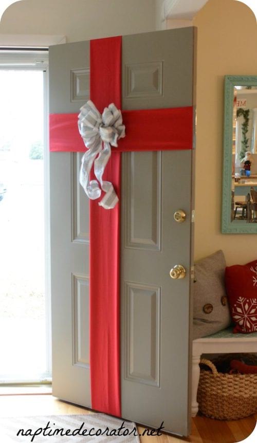 Puerta de entrada envuelta con una pequeña cinta roja para Navidad