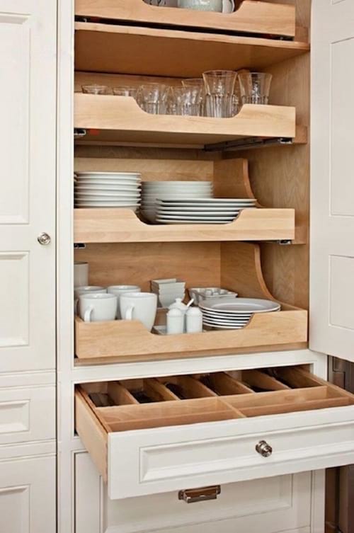 estantes telescópicos de madera en un armario para guardar todos los platos en la cocina