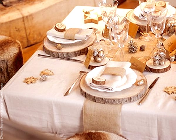 Fából készült rönkök, mint egy fehér terítőre terített asztal tányérokkal, poharakkal és evőeszközökkel