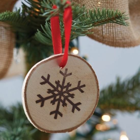 Julepynt til gran lavet af træstammer med et snefnug tegnet på