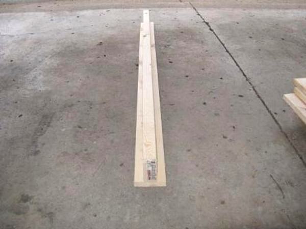 2 tablones de madera montados en forma de T, sobre suelo de hormigón.