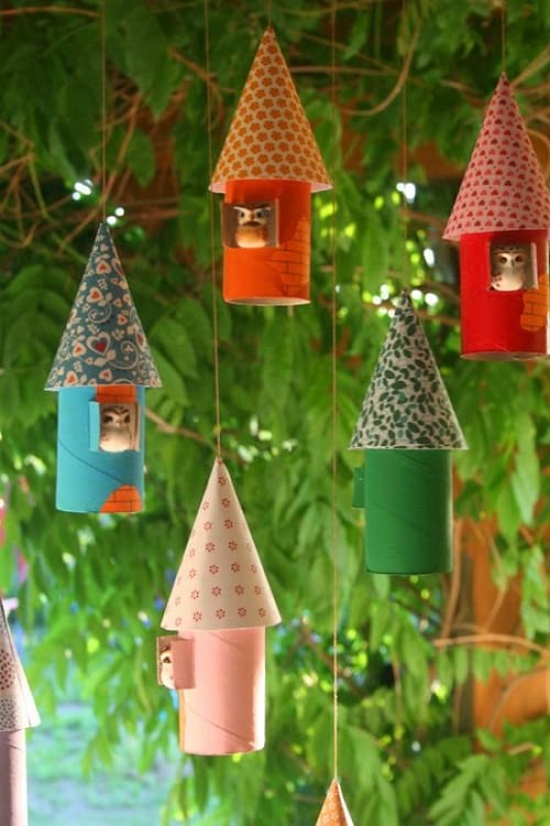 4 pequeños nidos de pájaros colgados de un árbol hechos con rollos de papel higiénico decorados