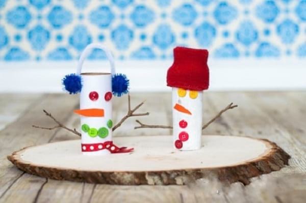Snemand lavet af toiletpapirruller limet på en dekorativ træplade