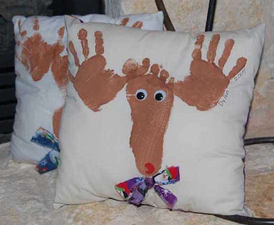 un cojín decorado con huellas de manos y pies para Navidad