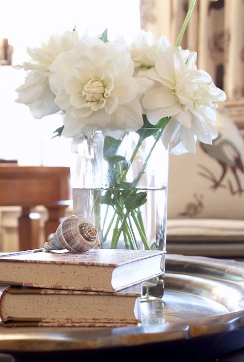 Varias flores blancas en un jarrón sobre una mesa de comedor