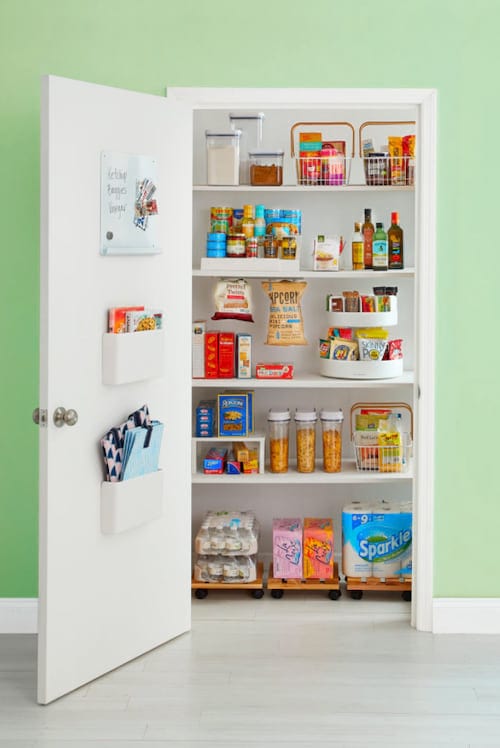 Gran armario blanco equipado con varios estantes que sirve de almacenaje para la comida.