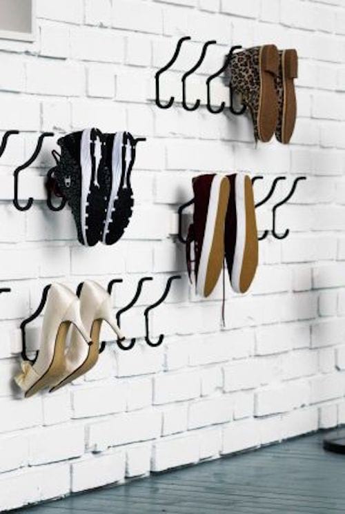 Varios pares de zapatos colgados de ganchos en la pared.