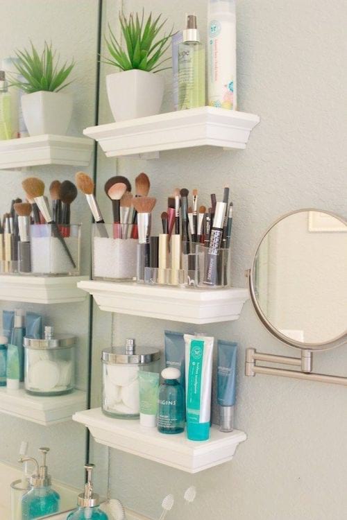 Pequeños estantes blancos colgados en la pared para maquillaje o utensilios de cuidado.