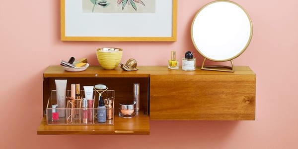 Un estante de madera con un cajón en el que se guarda el maquillaje en un bonito expositor.