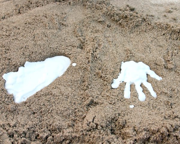 el molde de una mano y un pie se hace directamente en la arena