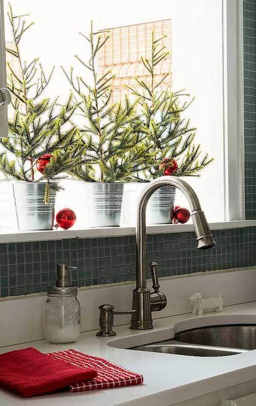 3 pequeños árboles de Navidad en el alféizar de la ventana de la cocina
