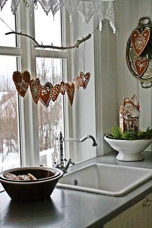 Una guirnalda de madera colgada en la ventana de la cocina con corazones rojos