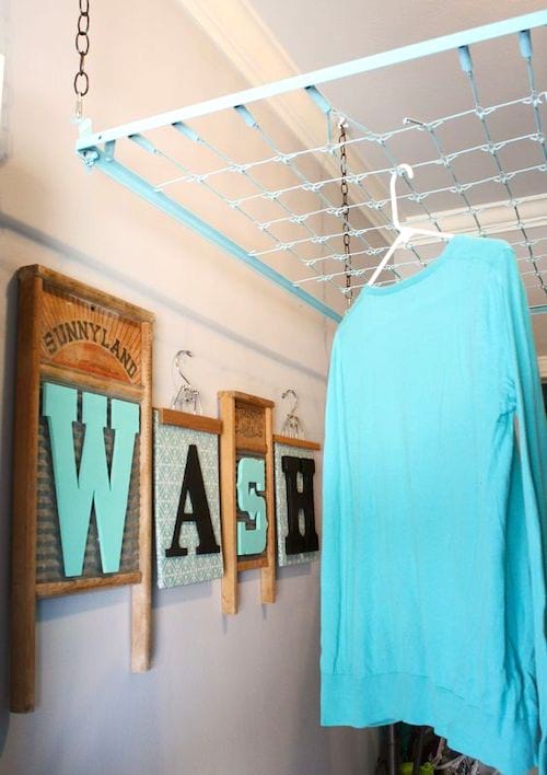 Un somier de metal reciclado como tendedero de techo en un cuarto de lavado para secar la ropa.