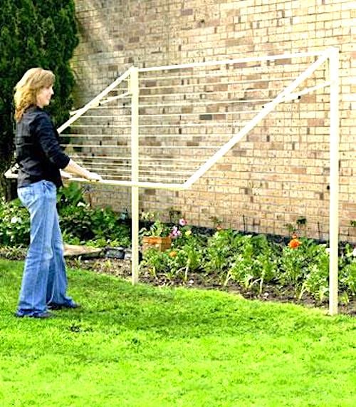 Una dona utilitza un estenedor retràctil que s'emmagatzema verticalment en un jardí.