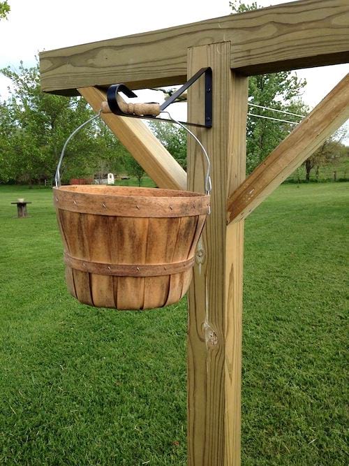 Un poste de madera para tender la ropa con una cesta, en un jardín.