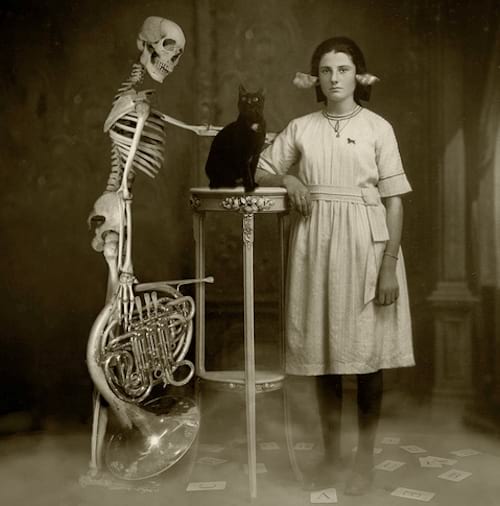 Pilli käes hoidev skelett, mille ees on must kass ja valgesse riietatud naine, kõrvades paber