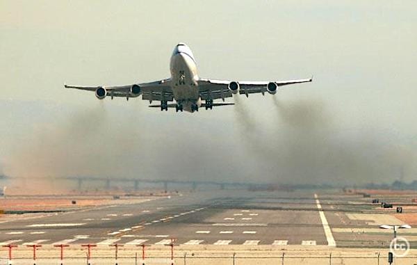 एक हवाई जहाज जो उड़ान भरता है और धुएं के बादल के साथ हवा में प्रदूषण से भरा होता है