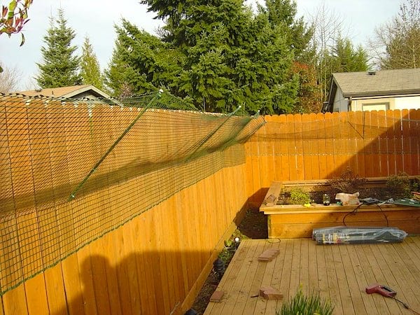 Una malla de alambre inclinada hacia atrás en una valla de madera.