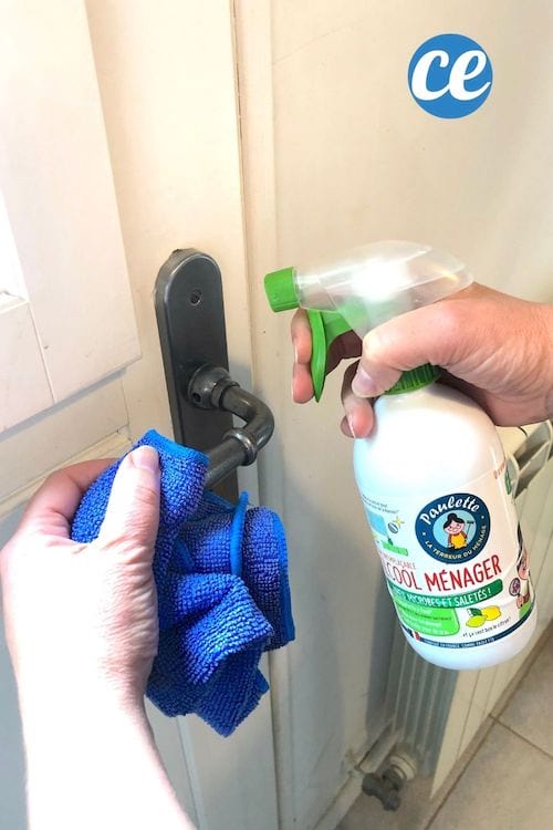 Spray de alcohol doméstico para desinfectar la manija de una puerta con un paño