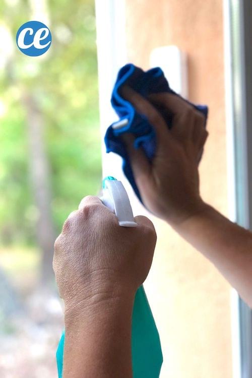 Una persona que limpia las ventanas con un trapo y spray de alcohol doméstico.