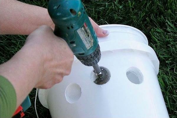Un taladro que perfora un balde de espuma de poliestireno para hacer un aire acondicionado doméstico.