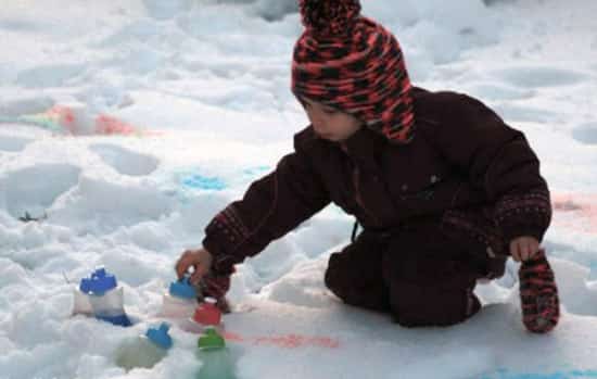 बर्फ में पेंट खेलता बच्चा