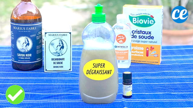 Una botella de líquido lavavajillas casero con los ingredientes en el fondo: bicarbonato de sodio, jabón negro, cristales de soda