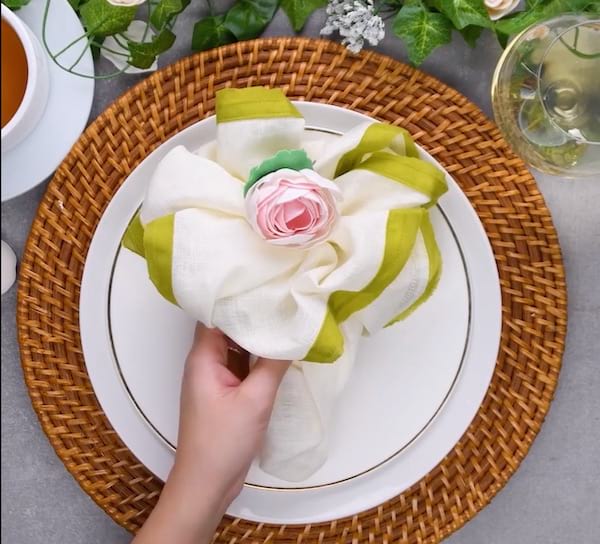 Tovalló plegat en forma de ram de flors col·locat sobre un plat blanc