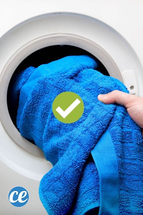 Una mano sacando una toalla azul de la secadora.