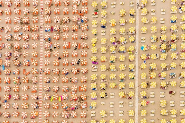 Playa en Italia dividida en dos partes, una con sombrillas amarillas y la otra en naranja