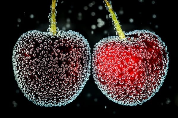 To kirsebær under vand med masser af små bobler