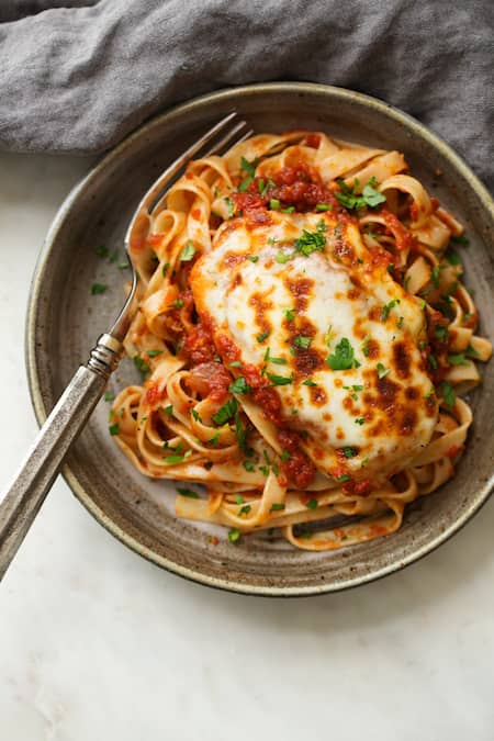 en tallerken kyllingemozzarella med tomatsauce serveret med pasta