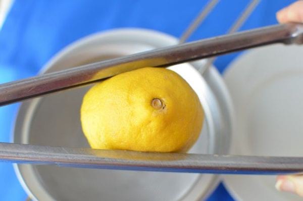 Use tongs to squeeze the juice from the lemon