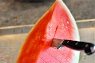 Un cuchillo que corta una sandía en rodajas horizontales.