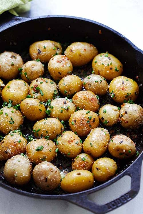 las patatas se asan en el horno y se sazonan con ajo y mantequilla de cebollino y se cubren con parmesano