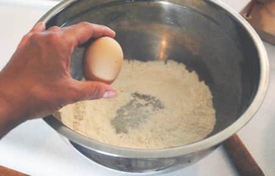 Tweede stap van het eenvoudige zelfgemaakte pannenkoekenrecept, voeg het ei toe aan de bloem.