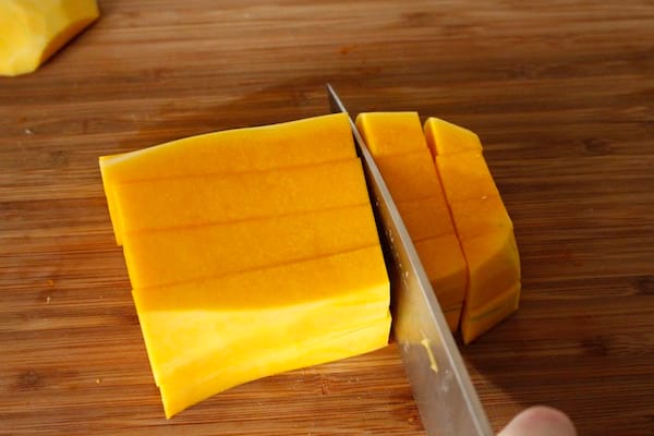 Un ganivet que talla una carbassa butternut a daus petits